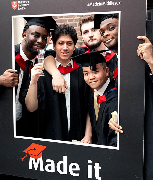 Graduates posing with a cardboard window displaying the words "Made it"